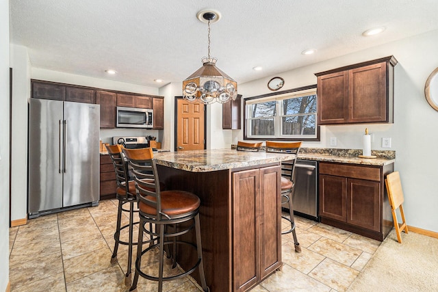 kitchen with stainless steel appliances, recessed lighting, dark brown cabinetry, a kitchen island, and a kitchen breakfast bar