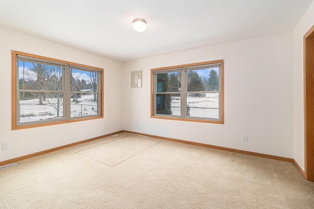 empty room featuring a healthy amount of sunlight, visible vents, and light colored carpet