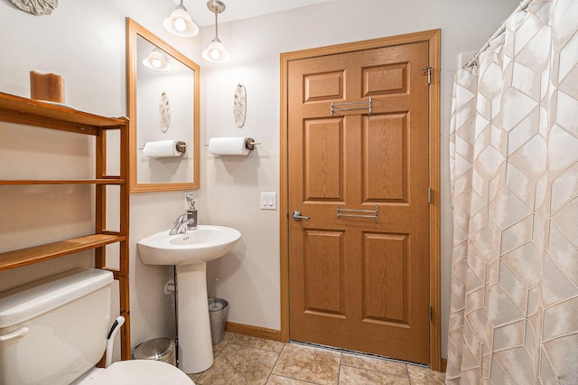 bathroom featuring curtained shower, baseboards, and toilet