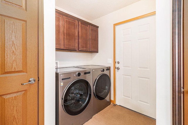 washroom featuring cabinet space, a textured ceiling, and washing machine and clothes dryer