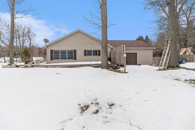 snow covered property featuring a garage and fence