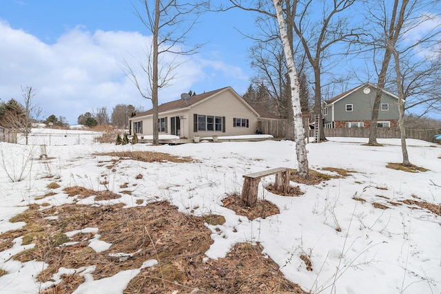 snow covered property featuring a garage and fence