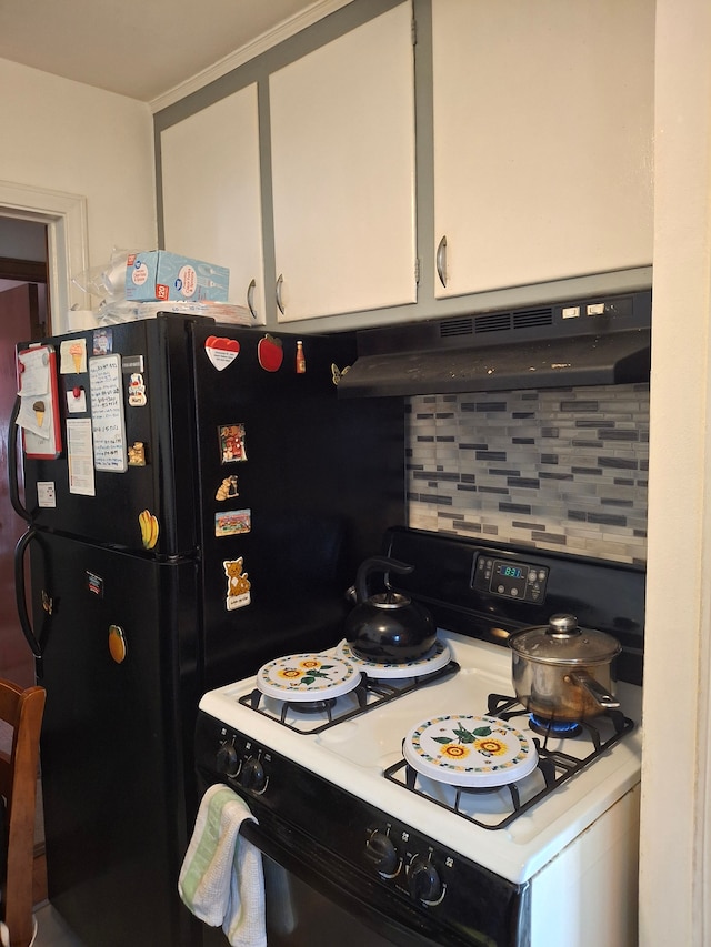 kitchen featuring under cabinet range hood, white cabinets, freestanding refrigerator, decorative backsplash, and gas range