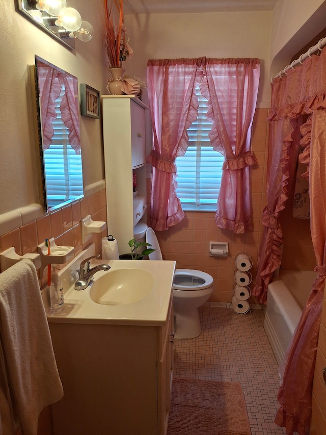 full bathroom with shower / bath combo, toilet, tile patterned flooring, vanity, and tile walls