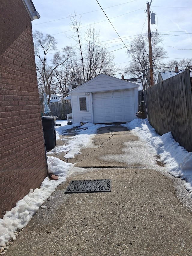 detached garage featuring driveway and fence