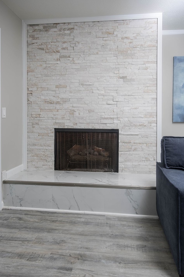 details featuring crown molding, a fireplace, baseboards, and wood finished floors