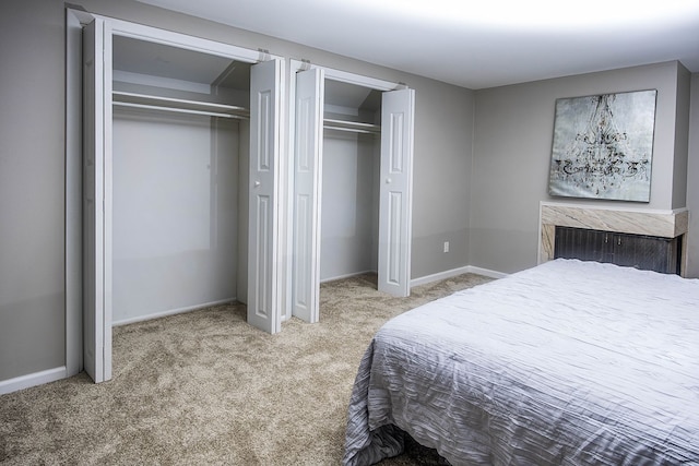 bedroom featuring carpet flooring, two closets, and baseboards