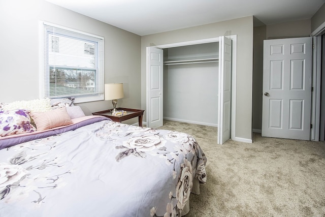 carpeted bedroom with a closet and baseboards