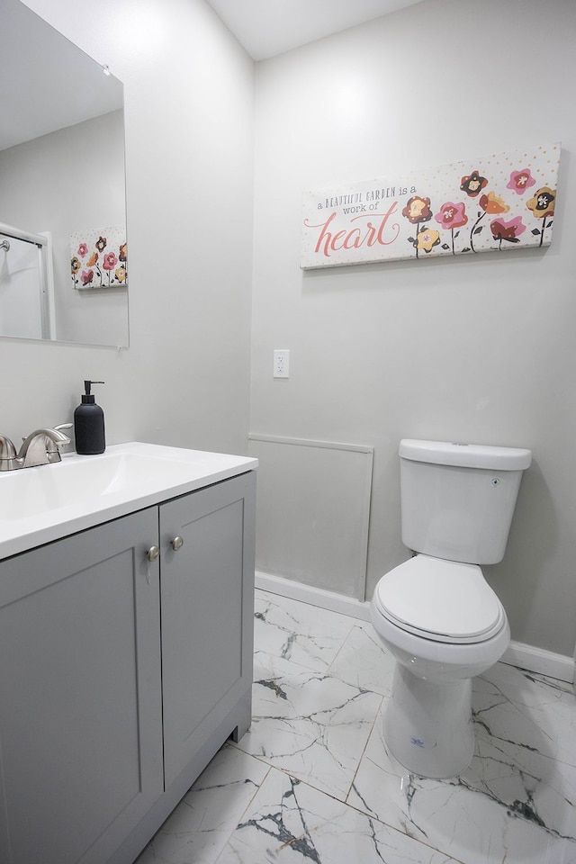 bathroom featuring marble finish floor, baseboards, vanity, and toilet