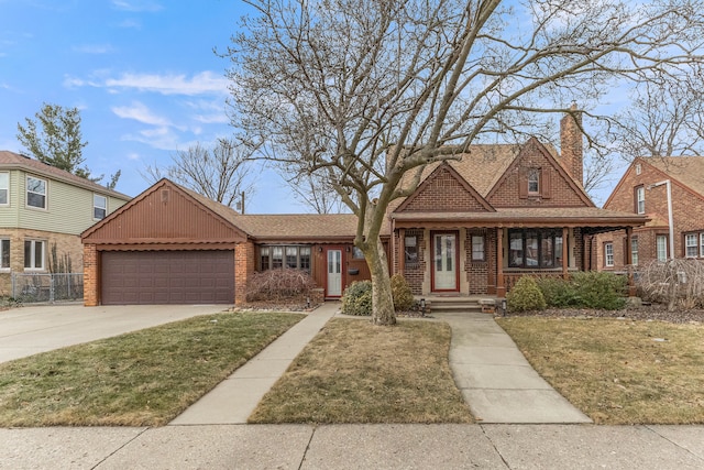 view of front facade with brick siding, a chimney, an attached garage, a front yard, and driveway