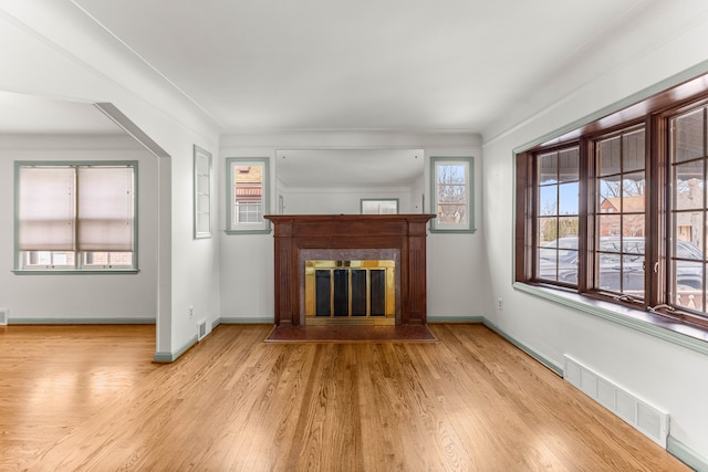 unfurnished living room featuring a fireplace with flush hearth, visible vents, baseboards, and wood finished floors