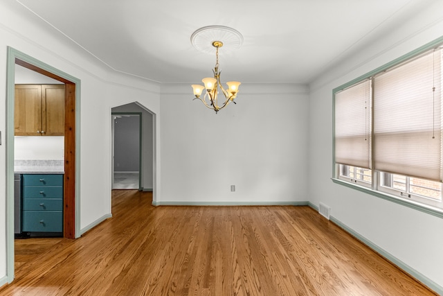 unfurnished dining area featuring baseboards, light wood-type flooring, and an inviting chandelier