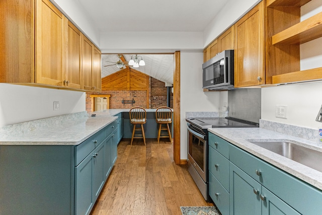 kitchen featuring lofted ceiling, stainless steel appliances, light wood-style floors, light countertops, and open shelves