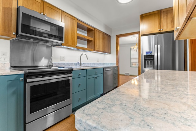 kitchen featuring stainless steel appliances, a sink, light wood-type flooring, light stone countertops, and open shelves