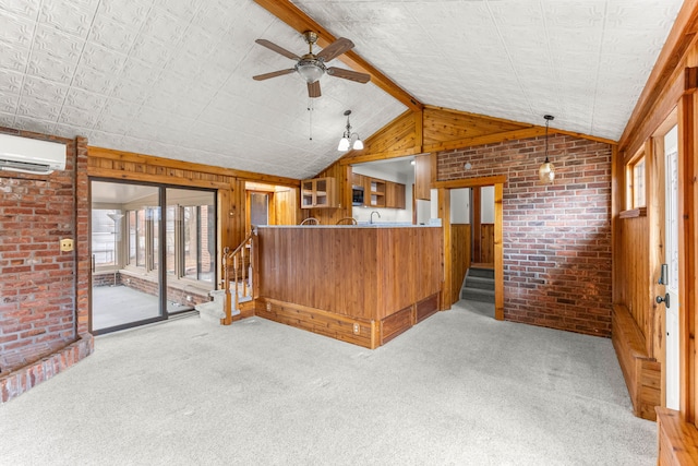 unfurnished living room featuring wooden walls, carpet floors, stairway, and brick wall