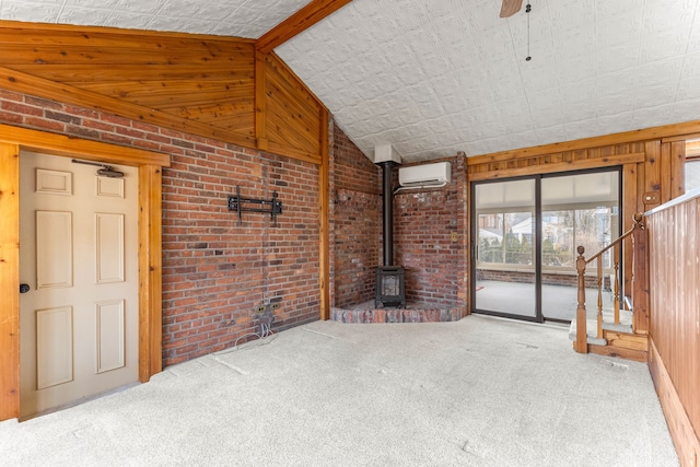 unfurnished living room with carpet, a wood stove, an AC wall unit, vaulted ceiling, and brick wall