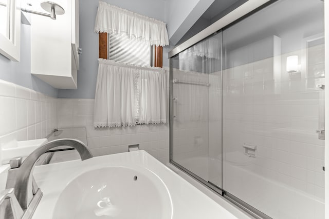 bathroom featuring a sink and bath / shower combo with glass door