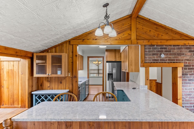 kitchen featuring lofted ceiling, wooden walls, stainless steel refrigerator with ice dispenser, and light countertops