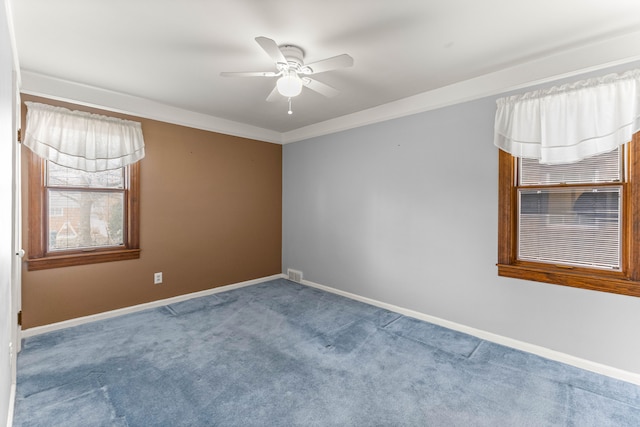 carpeted spare room with a ceiling fan, visible vents, crown molding, and baseboards