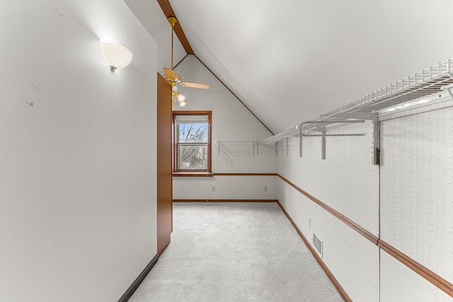 walk in closet with visible vents, vaulted ceiling, and light carpet