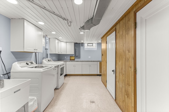 clothes washing area with cabinet space, electric panel, washing machine and clothes dryer, light floors, and a sink