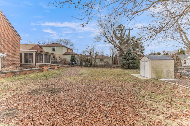 view of yard featuring an outbuilding, a sunroom, fence, and a storage unit