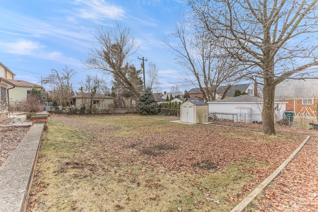 view of yard with a shed, fence, and an outbuilding