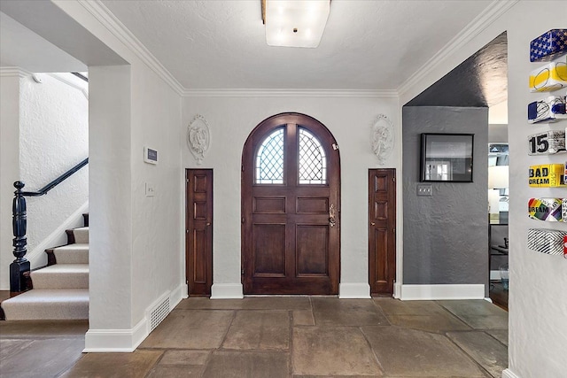 foyer featuring ornamental molding, stairway, stone tile flooring, and baseboards