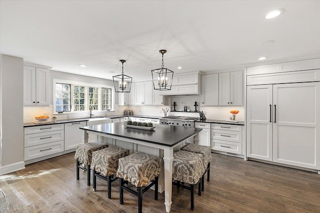 kitchen featuring dark countertops, dark wood-style flooring, paneled built in fridge, and a kitchen breakfast bar