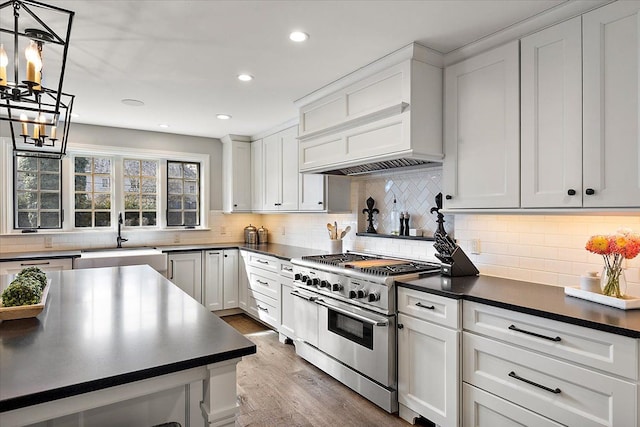 kitchen featuring dark countertops, double oven range, a sink, and wood finished floors