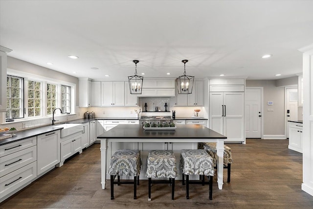 kitchen featuring paneled built in refrigerator, dark countertops, a kitchen bar, and decorative backsplash