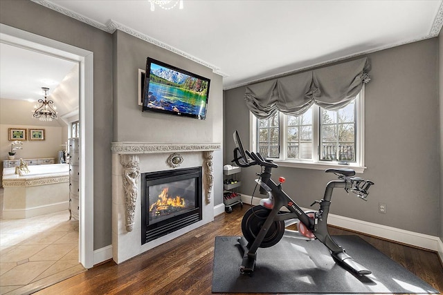 exercise area featuring baseboards, wood finished floors, and a glass covered fireplace