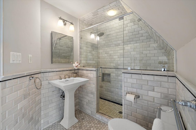 full bath featuring tile walls, wainscoting, a shower stall, and toilet