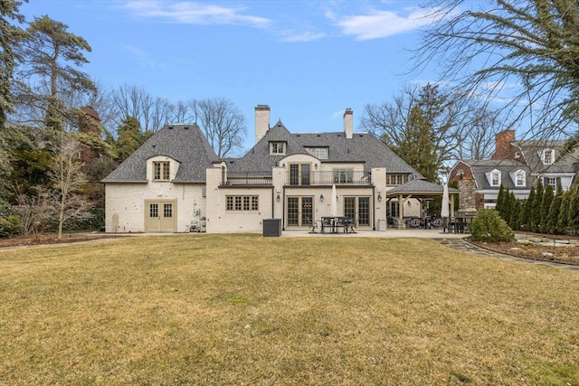 back of house featuring french doors, a chimney, a lawn, a gazebo, and a patio area