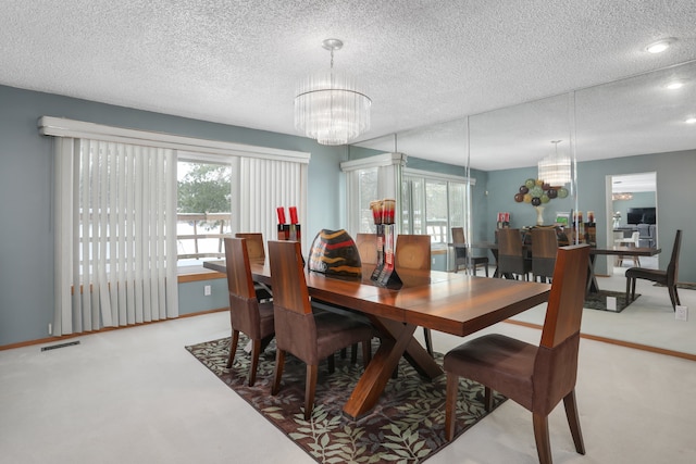 carpeted dining space with visible vents, a textured ceiling, baseboards, and an inviting chandelier