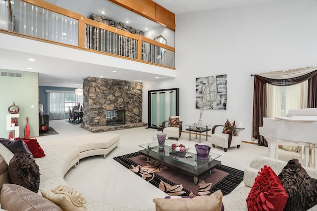 carpeted living room featuring visible vents, a fireplace, and a high ceiling