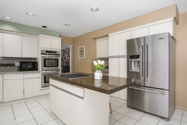 kitchen featuring a breakfast bar area, light tile patterned flooring, white cabinets, appliances with stainless steel finishes, and a center island