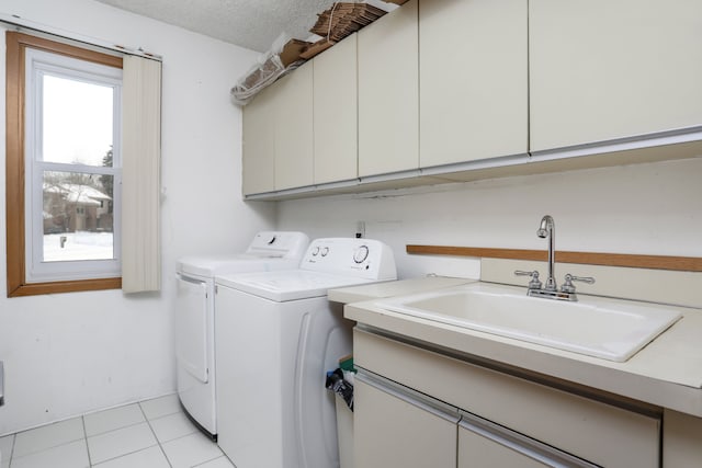 washroom featuring light tile patterned floors, cabinet space, a sink, a textured ceiling, and separate washer and dryer