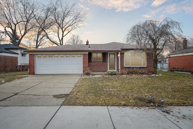 ranch-style home featuring a garage, a shingled roof, concrete driveway, a yard, and brick siding