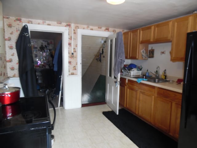 kitchen featuring a sink, light countertops, black appliances, brown cabinets, and light floors