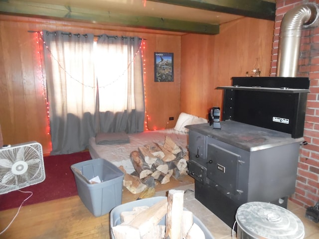 bedroom with wood walls, beam ceiling, and wood finished floors