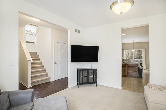 living room featuring stairs, carpet flooring, visible vents, and baseboards