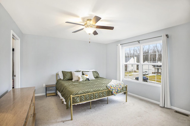 carpeted bedroom featuring a ceiling fan, visible vents, and baseboards