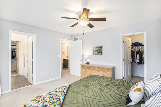 bedroom featuring ensuite bathroom, light colored carpet, visible vents, a spacious closet, and a closet