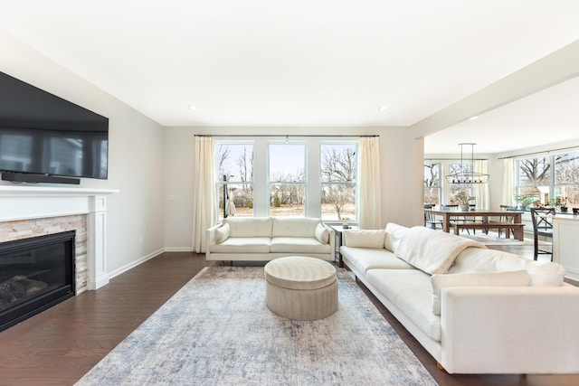 living room featuring a fireplace, baseboards, and wood finished floors