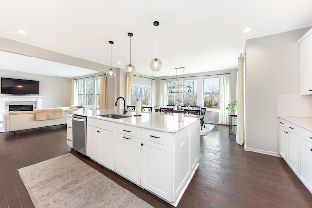 kitchen with dark wood-style flooring, a fireplace, tasteful backsplash, light countertops, and a sink