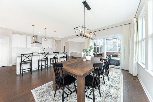 dining area featuring a notable chandelier, baseboards, visible vents, and dark wood-type flooring