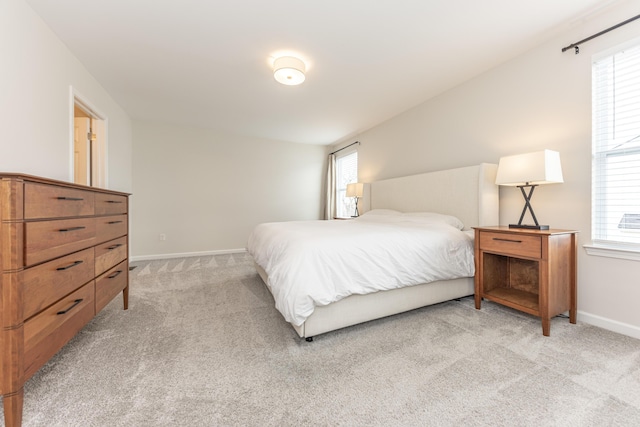 bedroom with baseboards and light colored carpet