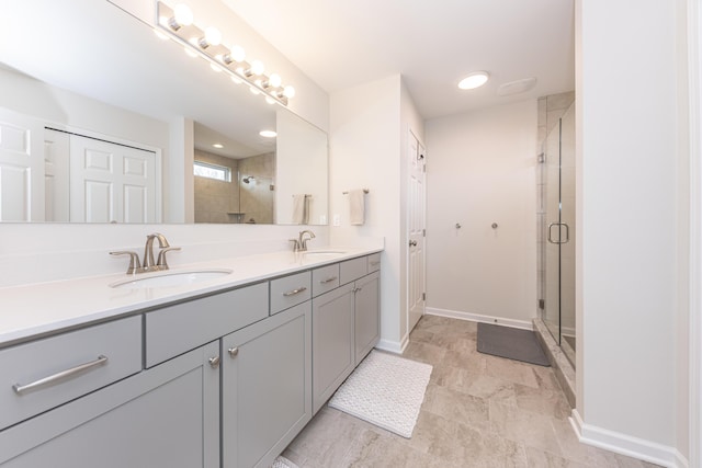 full bathroom with a sink, a shower stall, baseboards, and double vanity