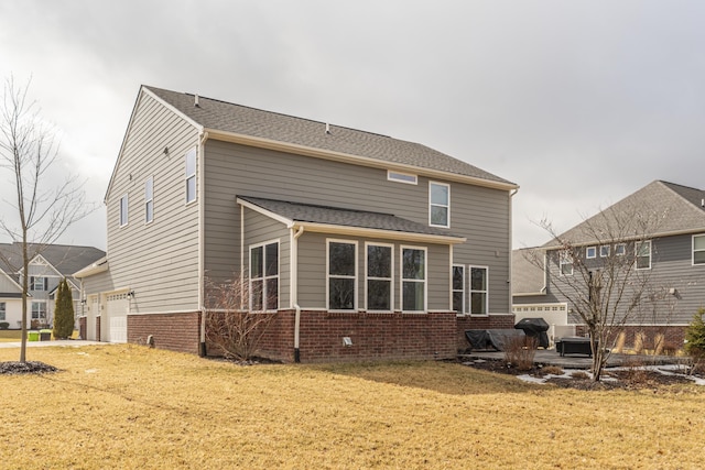 back of property with a garage, a yard, a shingled roof, and brick siding